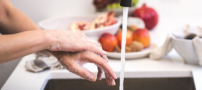 person washing their hands at a kitchen sink