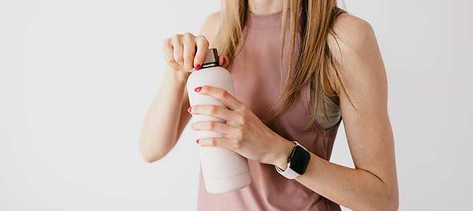 woman with hydrated skin opening a water bottle