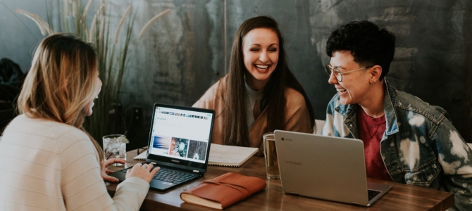 friends sitting at a coffee shop on laptops laughing