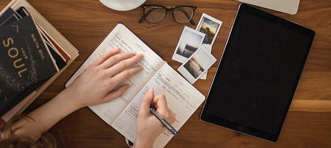 person sitting at a desk writing in a journal