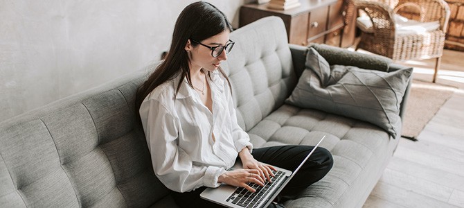 girl sitting on a couch with a laptop 